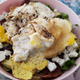 A yummy breakfast salad with egg, turkey bacon, spring mix, avocado and goat cheese